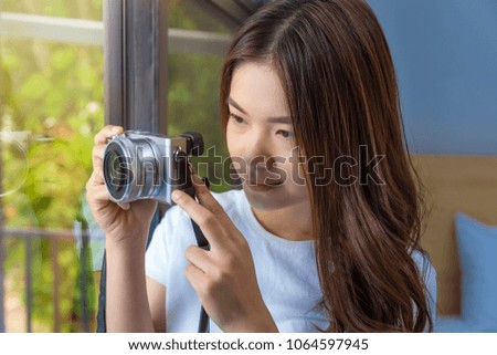 Young attractive asian woman using her camera to take picture of her garden through her bedroom window, good for hobby or fun lifestyle theme