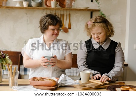 Girl in studio,Down syndrome, the concept of health and medical examination  with special needs,Down syndrome, concept of health with special needs. Two girls with Idrom down in the kitchen at home.  Royalty-Free Stock Photo #1064600003
