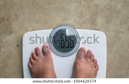 Fat man standing on digital Weight Scale.
