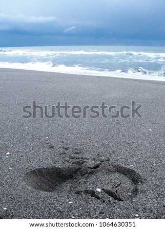 Foot print in dark sand on the beach