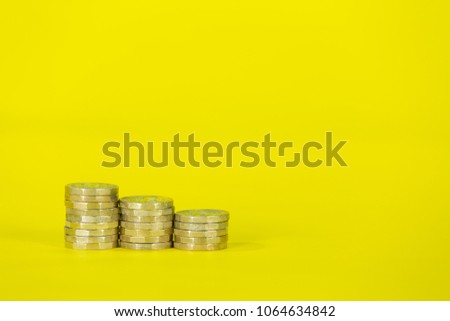 Stacked Gold Coins on a Bright Yellow Background Royalty-Free Stock Photo #1064634842