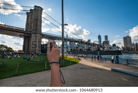 Woman's hand taking a photo of the Brooklyn bridge and Manhattan skyline in New York city