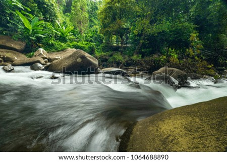 scenic of flow of waterfall with rock and green forest for natural travel