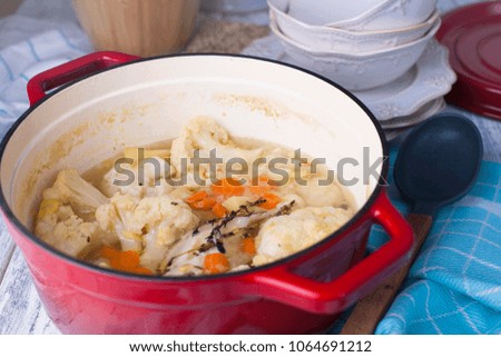Cauliflower cooked in a red cast iron. A blue towel. Free space for text. Family dinner. Vegetables. Ready-made dish