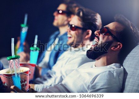Group of happy friends sitting in cinema watch film and eating popcorn