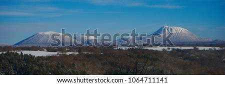 Panoramic view of the puy de dome and the puy de come under the snow, blue sky and forest Royalty-Free Stock Photo #1064711141