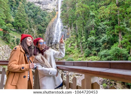 Group of happy tourism gossip and laughing with background of Nachi waterfalls at Kumano World heritage , wakayama , Japan national park. Group of young people looking at photo look so happy