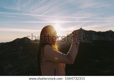 woman using phone in mountains at sunset with beautiful view. Picturesque landscape background.