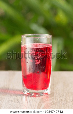 Glass and red drink on a table on a green background