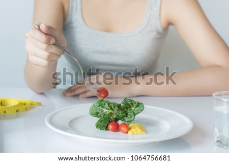 Eat less and eat healthy. person eating vegetable in dinner during control calories on dieting. Royalty-Free Stock Photo #1064756681