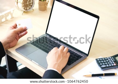 Businessman hand touching and using laptop with blank white desktop screen with credit credit in hand for shopping some goods on internet and making online payment.