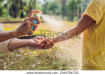 dad and son use mosquito spray.Spraying insect repellent on skin outdoor Royalty-Free Stock Photo #1064786720