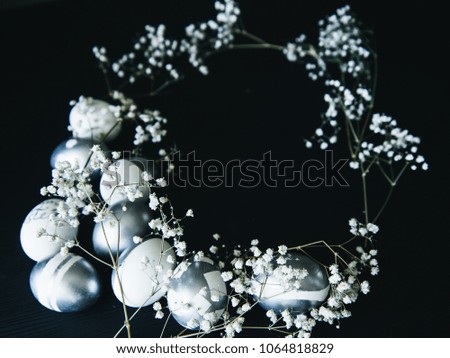 Diverse Group of silver Easter eggs with white flowers on black background, copy space, stylish original idea, selective focus