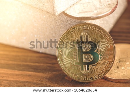 Golden Bitcoin placed near glitter silver gift box