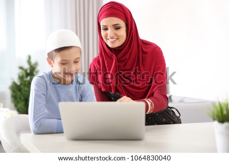 Muslim woman using laptop with her son at home