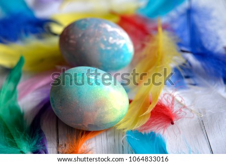 Colored Easter eggs on a wooden background among colored feathers