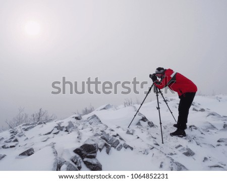 Silhouette of photographer with tripod in the fog.. Photographer works in foggy winter landscape