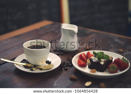 Hot coffee in white cup on wood background,Brownie with Fresh strawberry on white plate