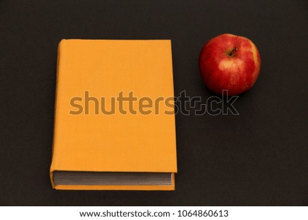 a big red apple and a closed yellow book