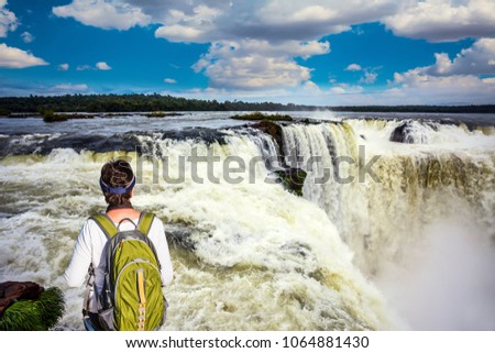 Energetic woman with a tourist backpack watching waterfalls the Garganta del Diablo/ Devil's Throat. Concept of active and extreme tourism Royalty-Free Stock Photo #1064881430