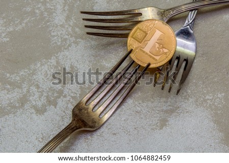 golden Litecoin and silver fork on abstract background