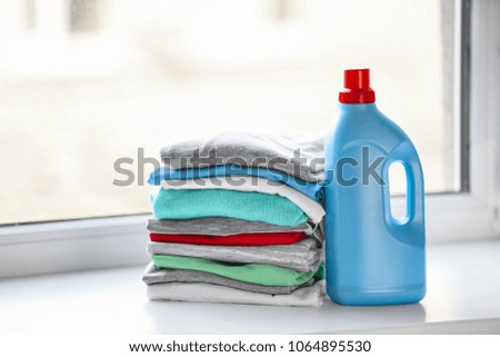 Stack of clothes and laundry detergent on windowsill