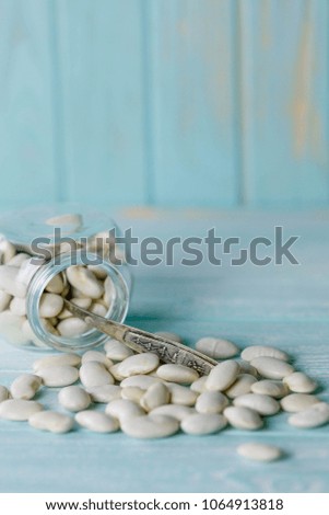 White beans in a glass jar with spoon on blue rustic old wooden background