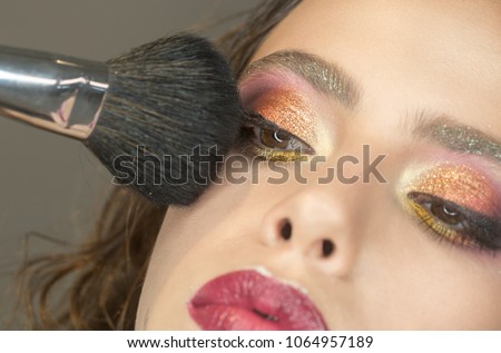 Beautiful woman applying foundation powder with makeup brush.