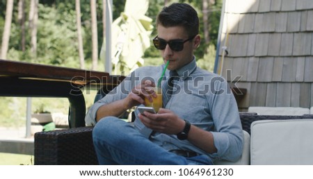 Young businessman with sunglasses siting outside and working