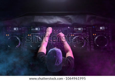 Charismatic disc jockey at the turntable. DJ plays on the best, famous CD players at nightclub during party. EDM, party concept. Top view. Aerial view. Royalty-Free Stock Photo #1064961995