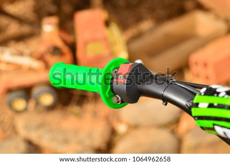 handlebar and clutch of motorcycle cross with green grip and old crane truck on the background blurred.