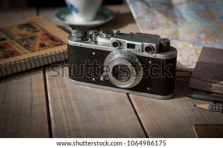 Vintage analogue film camera on a wooden table, map, notepad, pencil, cup. Copy space