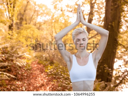 Woman meditating against blurry forest