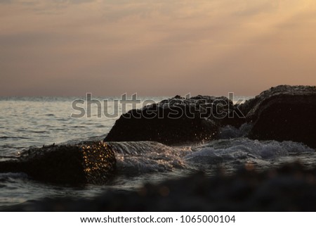 Sea spray at sunset, waves on the rocks, sunbeams at sunset, selective focus
