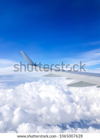 Picture of airplane wing, cloudy sky from porthole