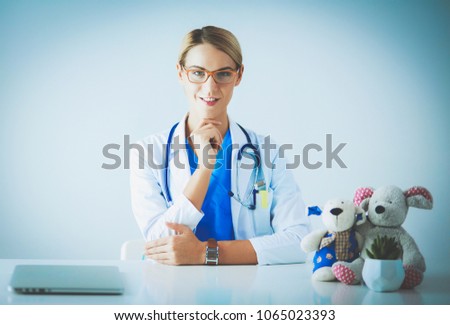 Beautiful young smiling female doctor sitting at the desk.