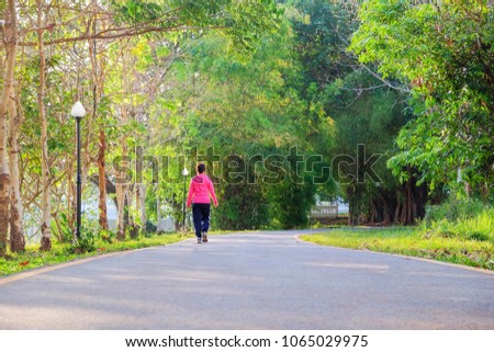 A front selective picture of a green natural park with a jogging man at background 