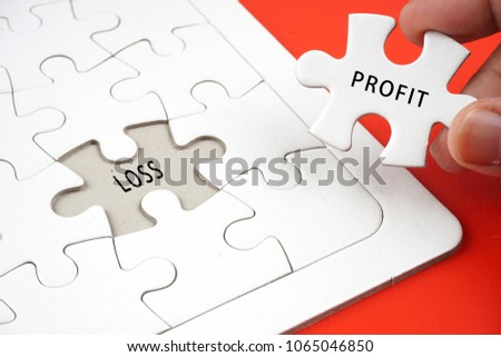 hand holding a piece of puzzle with wording 'PROFIT' and the empty space with 'LOSS' wording