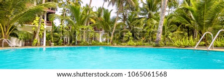 Beautiful idyllic resort with swimming pool among palm trees. Scenic pool with clean blue water in summer. Nice panoramic view of sunny tropical hotel. Horizontal banner of luxury resort.