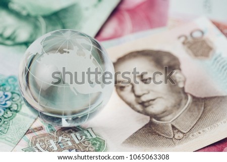 US and China trade war, tariff, tax barrier, decoraton glass globe with the side of United States map on China yuan banknotes.