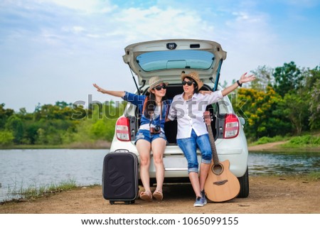 Couple of traveler sitting on hatchback of car and enjoy for view of nature near the lake during holiday.Young couple tourist enjoying on vacation. 