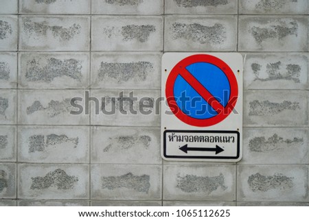 A sign of "No parking along the line" on the grey wall
