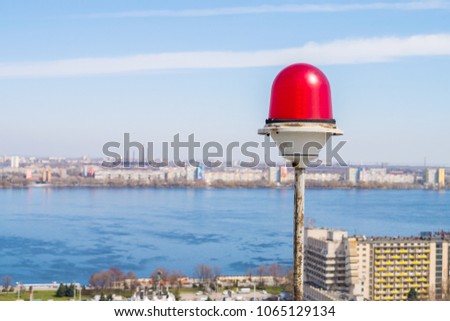 Obstruction Lights close-up. Light-signaling is based on a blue sky and a river. Red alarm lamp.
