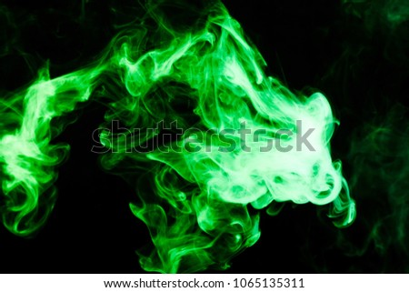 Dense multicolored smoke of    green colors on a black isolated background. Background of smoke vape