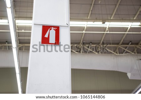 Fire extinguisher sign hanged on the post inside the shopping mall.
