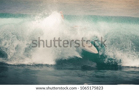 Image of Surfer on Blue Ocean Wave in Bali, Indonesia. Surfer riding in tube. Short surfboard. Deep adventure