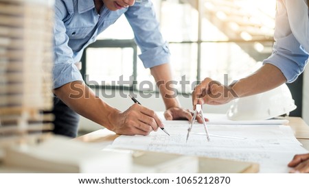 Close-up Of Person's engineer Hand Drawing Plan On Blue Print with architect equipment, Architects discussing at the table, team work and work flow construction concept. Royalty-Free Stock Photo #1065212870