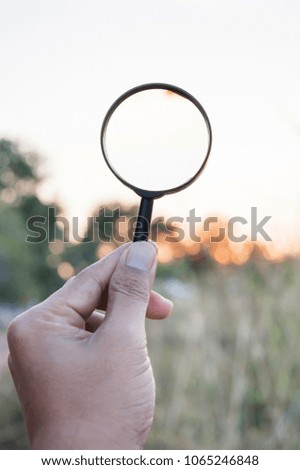 Hand hold magnifying glass lens refracts light rays, vertical
