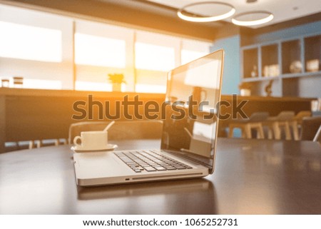 laptop, cup and diary on table in office at sunrise