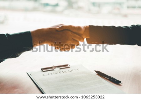 Business people negotiating a contract handshake between two colleagues